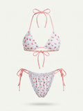 A two-piece string bikini set featuring a white base with a pink strawberry print, paired with pink and white gingham halter top and side-tie bottoms, shown against a light off-white background.