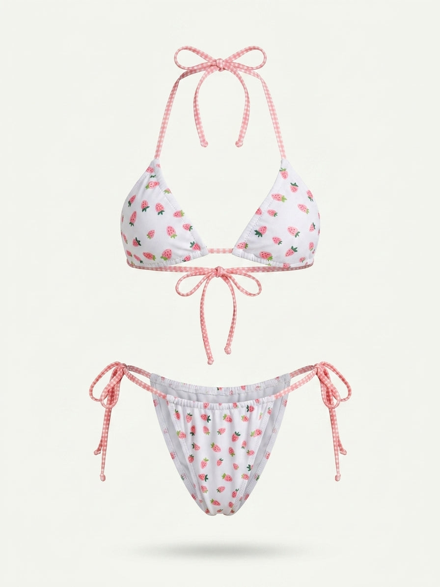 A two-piece string bikini set featuring a white base with a pink strawberry print, paired with pink and white gingham halter top and side-tie bottoms, shown against a light off-white background.