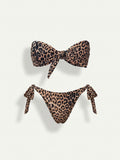 A two-piece bikini set with a brown, beige, and black leopard print pattern. The top is a bandeau-style bikini top with a large front bow, and the bottom is a high-cut bikini bottom with side ties, both displayed on a light off-white background.