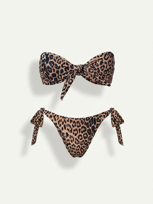 A two-piece bikini set with a brown, beige, and black leopard print pattern. The top is a bandeau-style bikini top with a large front bow, and the bottom is a high-cut bikini bottom with side ties, both displayed on a light off-white background.